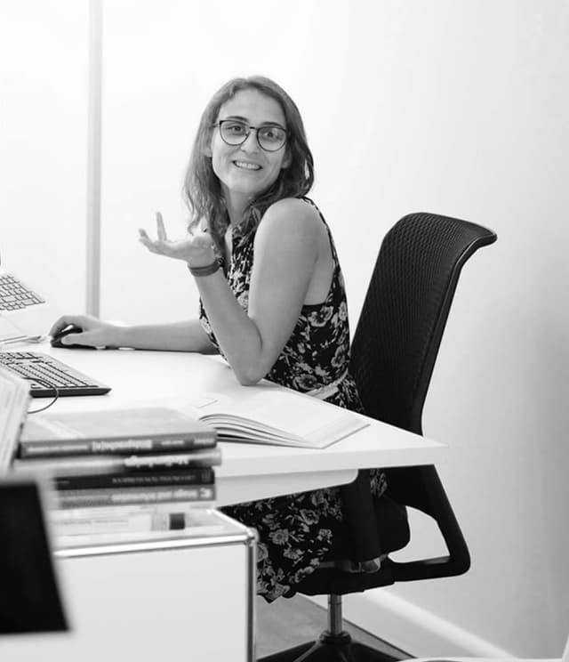 One of our colleagues at her desk, explaining a concept 