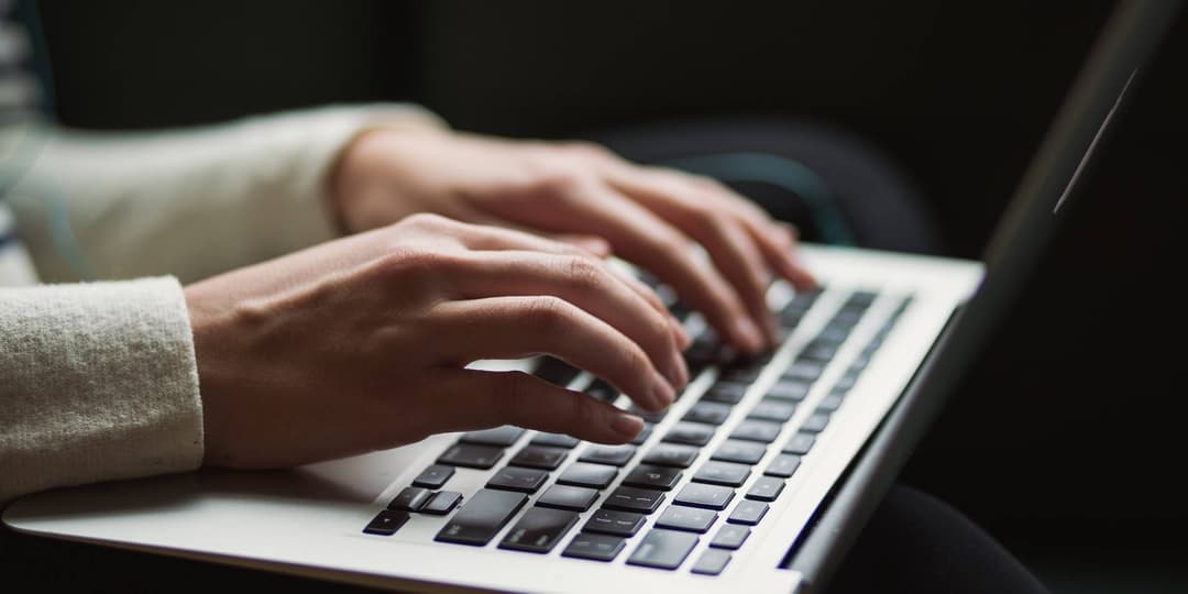 Texter arbeitet an einem aufgeschlagenen Laptop