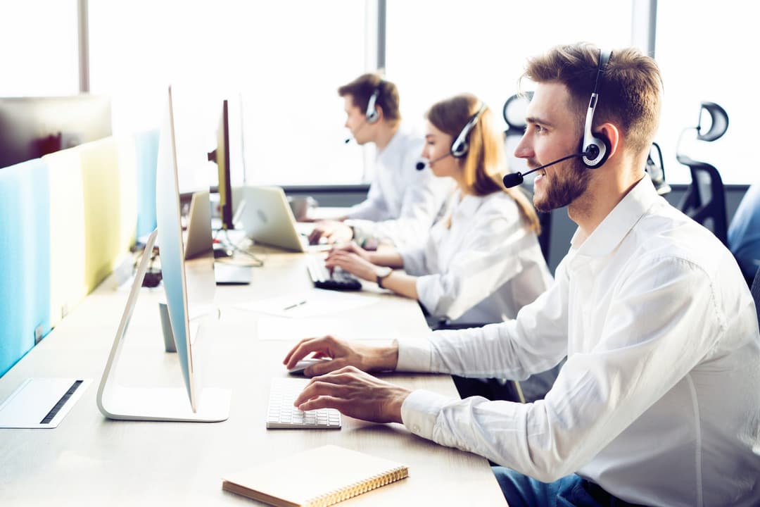 Mitararbeitende eines Callcenters telefonieren am Computer. 