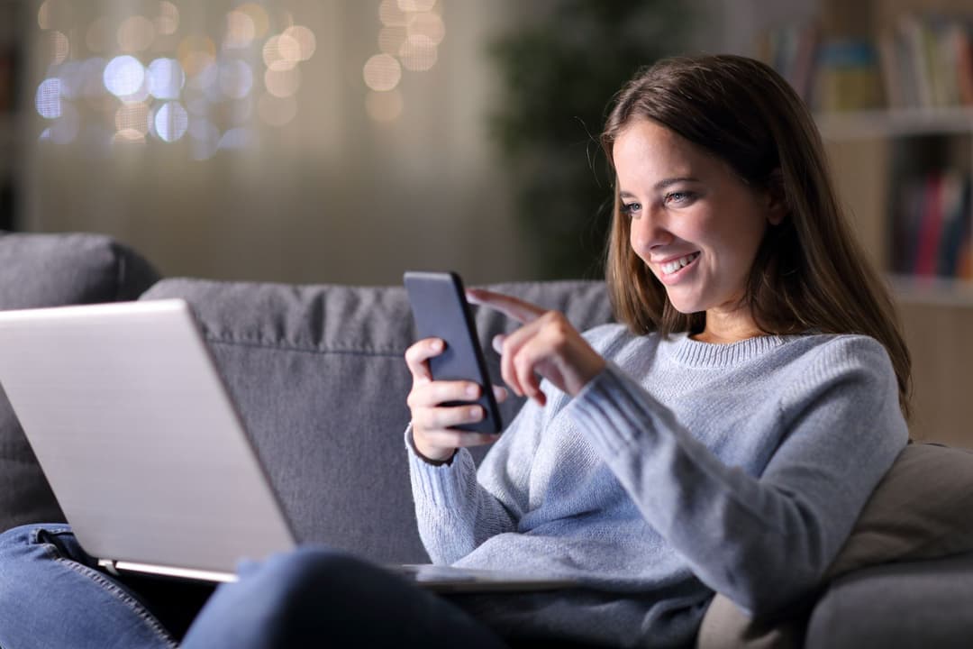 Junge Frau mit Smartphone und Laptop. 