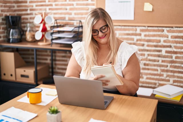 Frau, die bei einer Tasse Kaffee Notizen macht, während sie an der Entwicklung ihrer Personal Brand arbeitet.