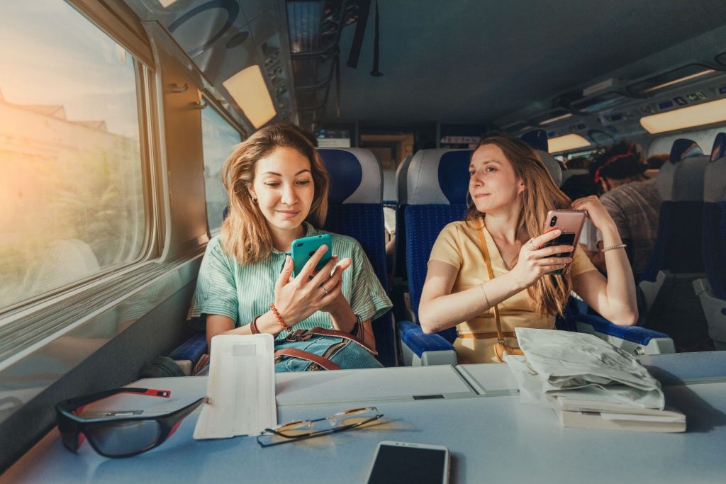 Zwei Frauen sitzen im Zug und schauen auf ihre Smartphones. 