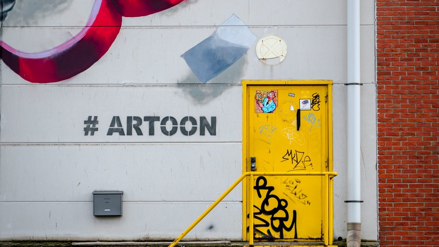 Mauer mit einem Graffito und dem aufgemalten Hashtag #Artoon. 