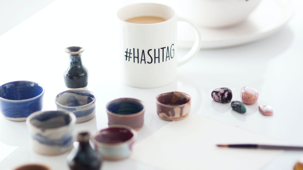 Tasse auf einem Schreibtisch mit dem Schriftzug “#Hashtag”.